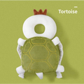 A plush tortoise-shaped toddler head protection pad with a white head, green stitched shell, and bunny ear mesh design