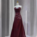 A strapless skirt evening gown in glossy burgundy leather with a fitted bodice and flowing floor-length skirt