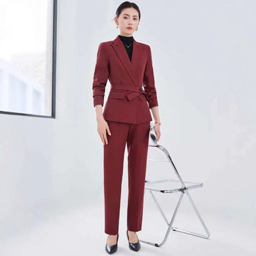 A tailored burgundy long sleeve two piece set with a belted waist blazer and matching sleeve small suit trousers