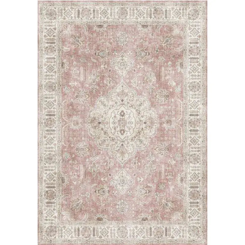 A burgundy ornate short pile area rug with faded dusty rose background and cream floral geometric patterns