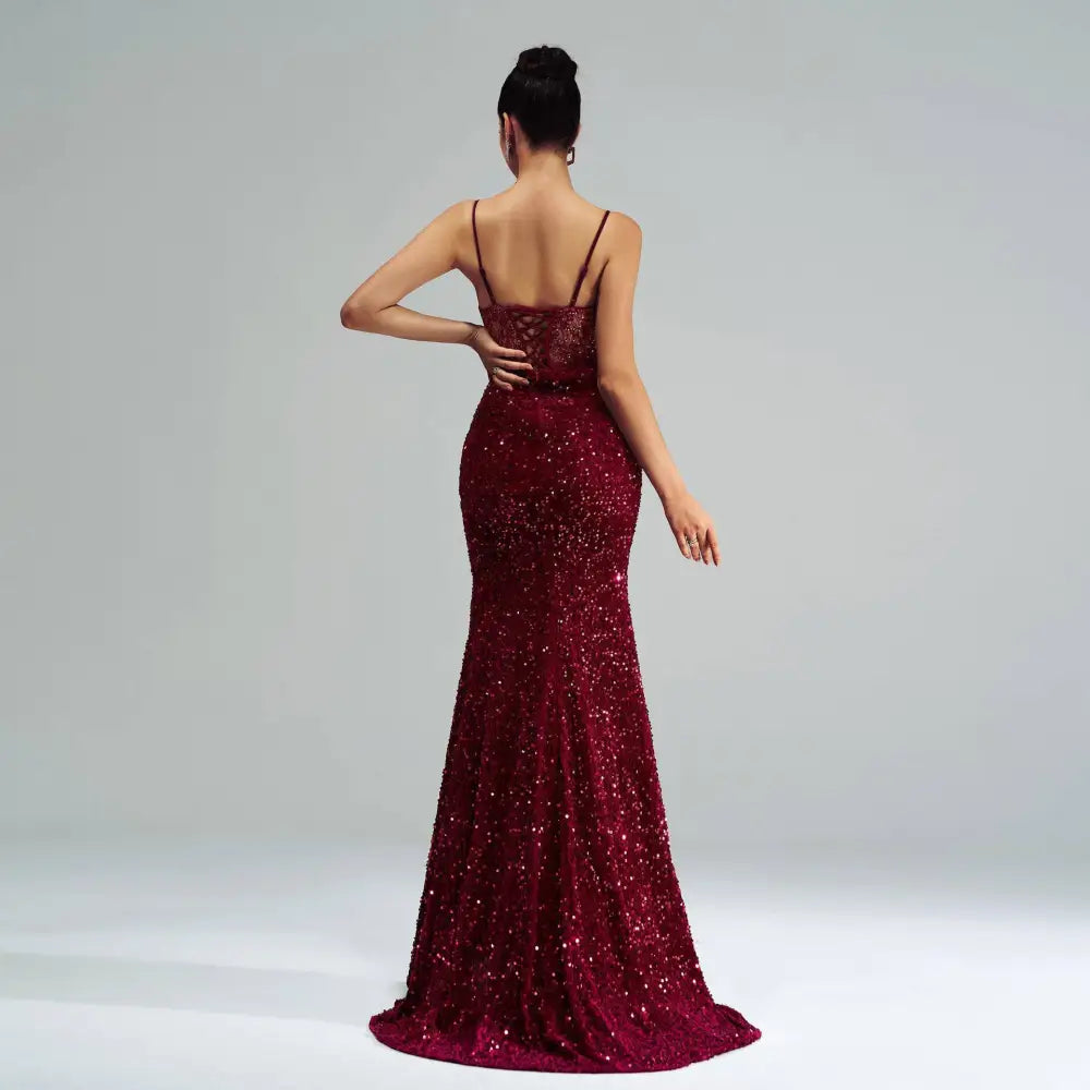 Back view of a burgundy sleeveless sequined mermaid gown with lace detailing and a high slit evening dress design