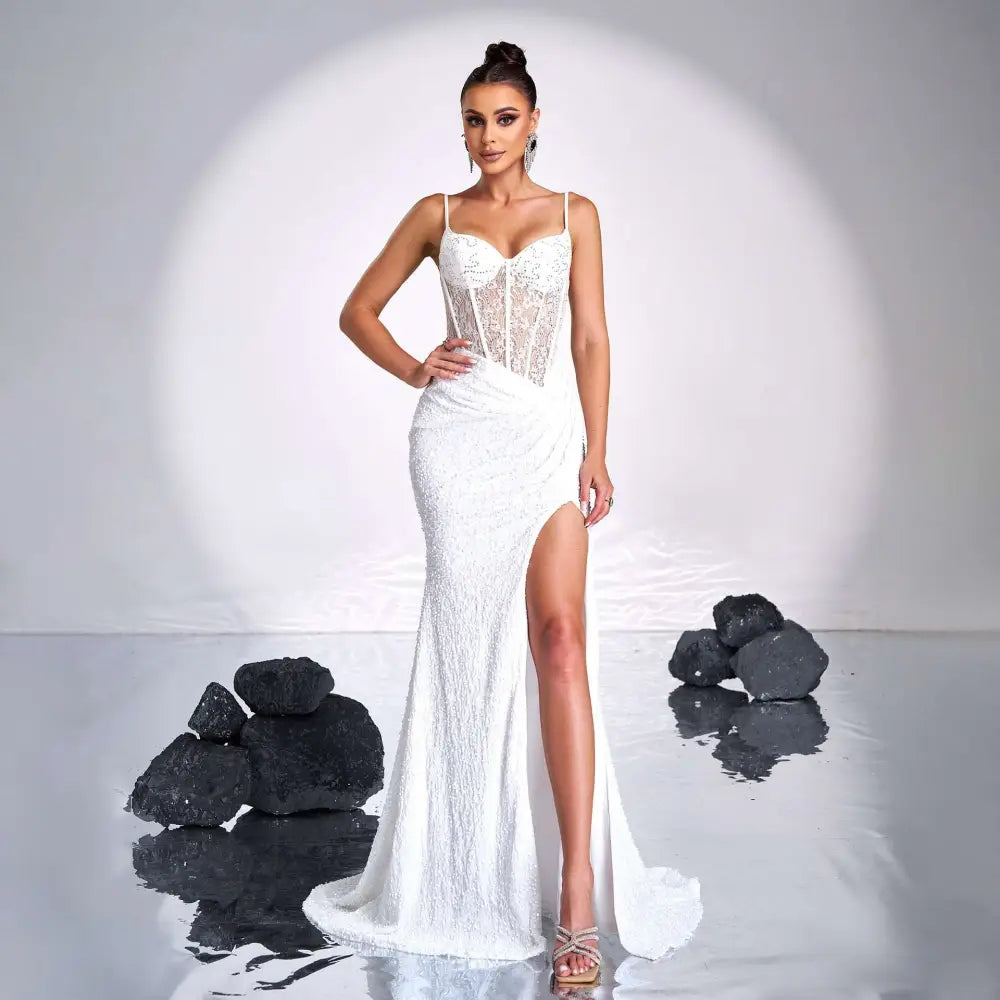 A white form-fitting mermaid gown with a lace bodice and high slit complementing burgundy sleeveless sequined high slit evening dress
