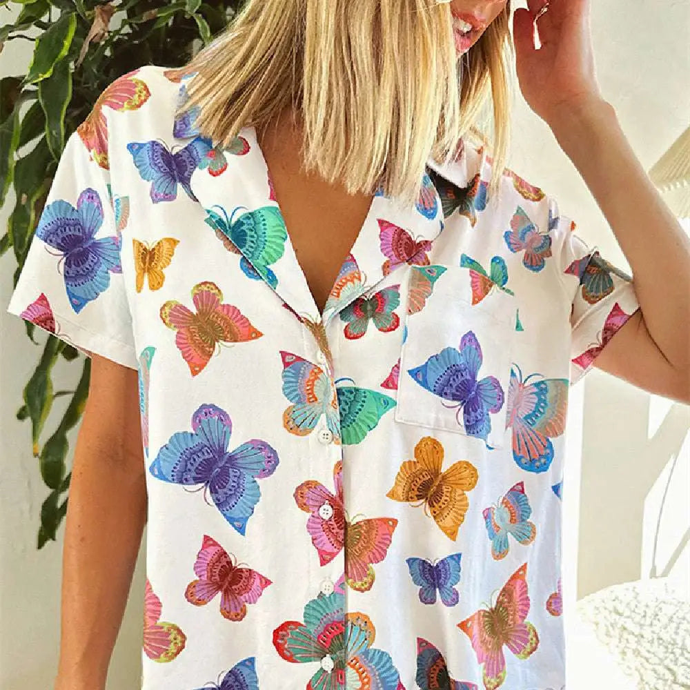 A white short sleeve homewear suit with a vibrant butterfly print in blue purple pink orange and green colors