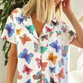 A white short sleeve homewear suit with a vibrant butterfly print in blue purple pink orange and green colors