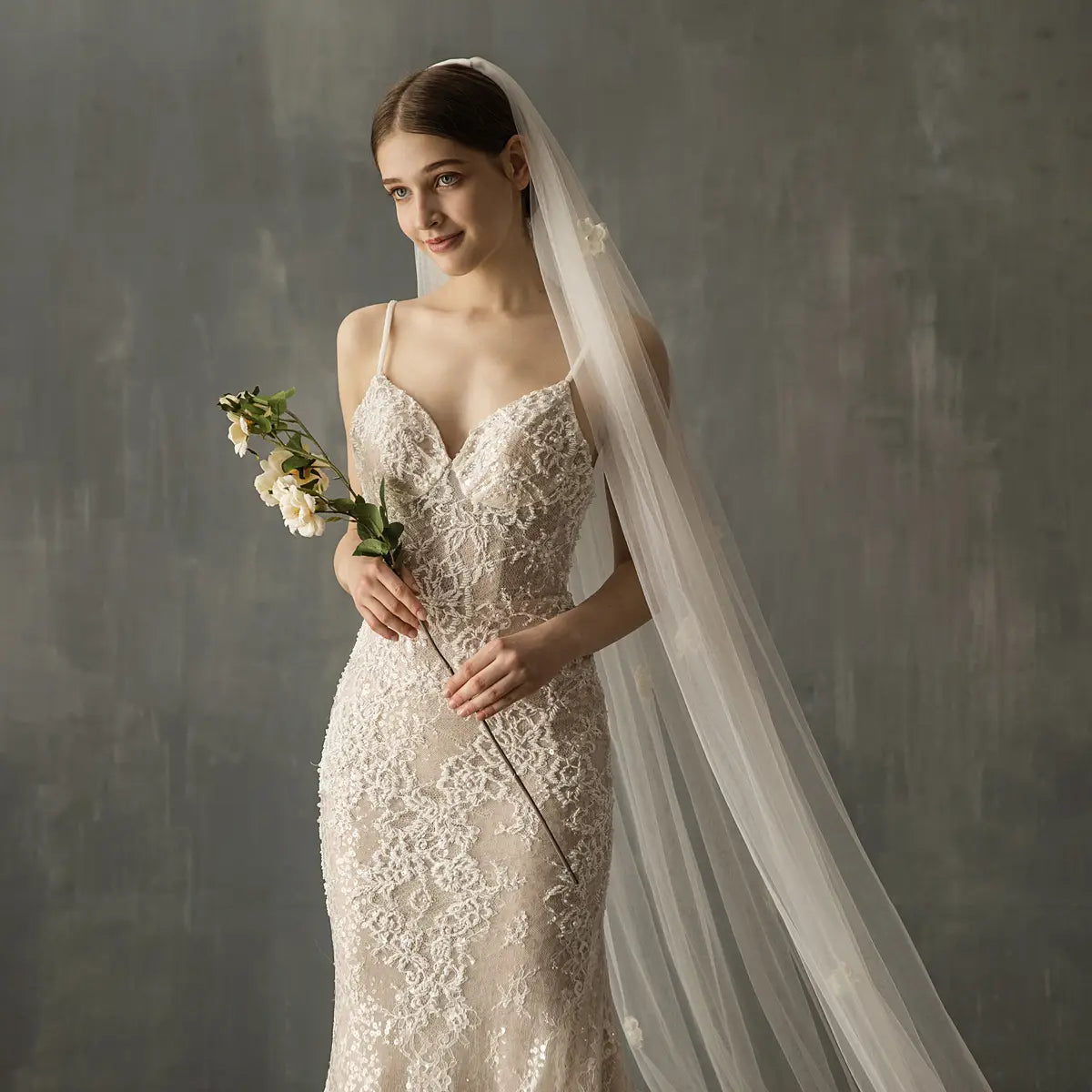 A delicate ivory lace bridal church wedding gown with fitted silhouette, intricate floral patterns, and a matching sheer veil, designed as a church wedding pearl long tail gown.