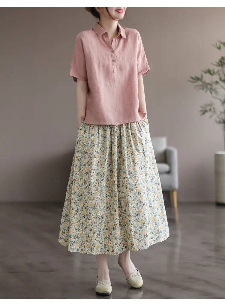 a soft pink short-sleeved linen blouse with a classic collar and button front paired with an artistic floral washed cotton midi skirt.
