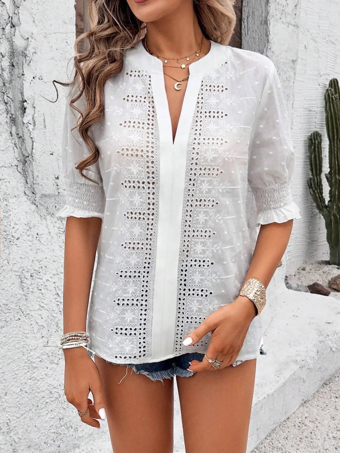 White eyelet blouse with short puff sleeves and a hollow hair ball detail featuring a v-neckline.