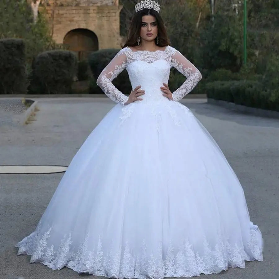 White vintage lace applique wedding dress in white featuring a fitted bodice, long lace sleeves, and intricate floral embroidery along the neckline, hemline, and cuffs.