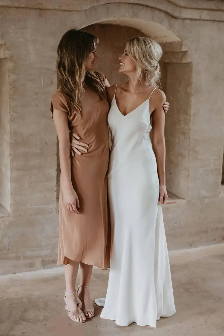 a flowing white satin evening gown with a v-neckline, thin straps, and a train captured in a train brigade shot