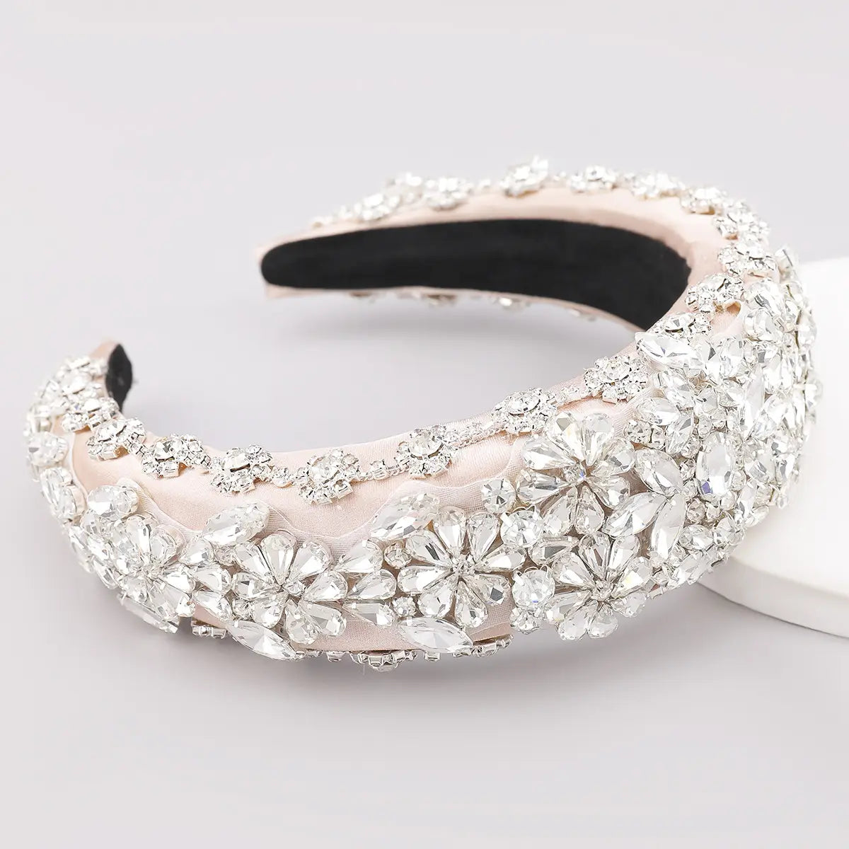 A blush pink satin headband with intricate silver crystal flower embellishments is a fashionable personality hair accessory made from hair accessories fabric.