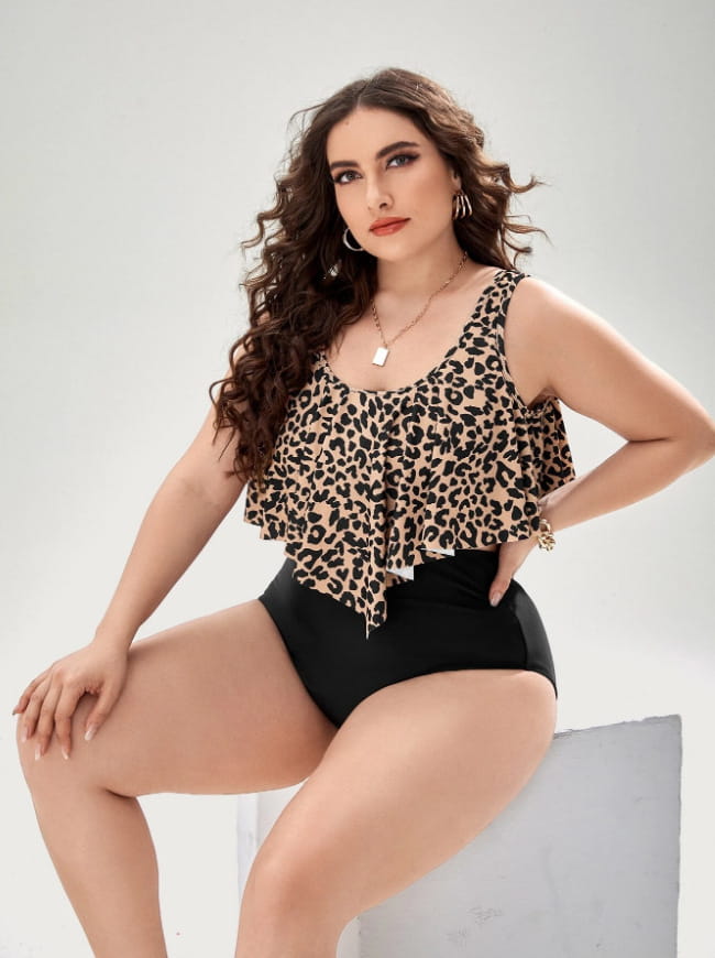 A stylish plus-size leopard print swimsuit featuring a ruffled sleeveless tankini top paired with black high waist shorts.