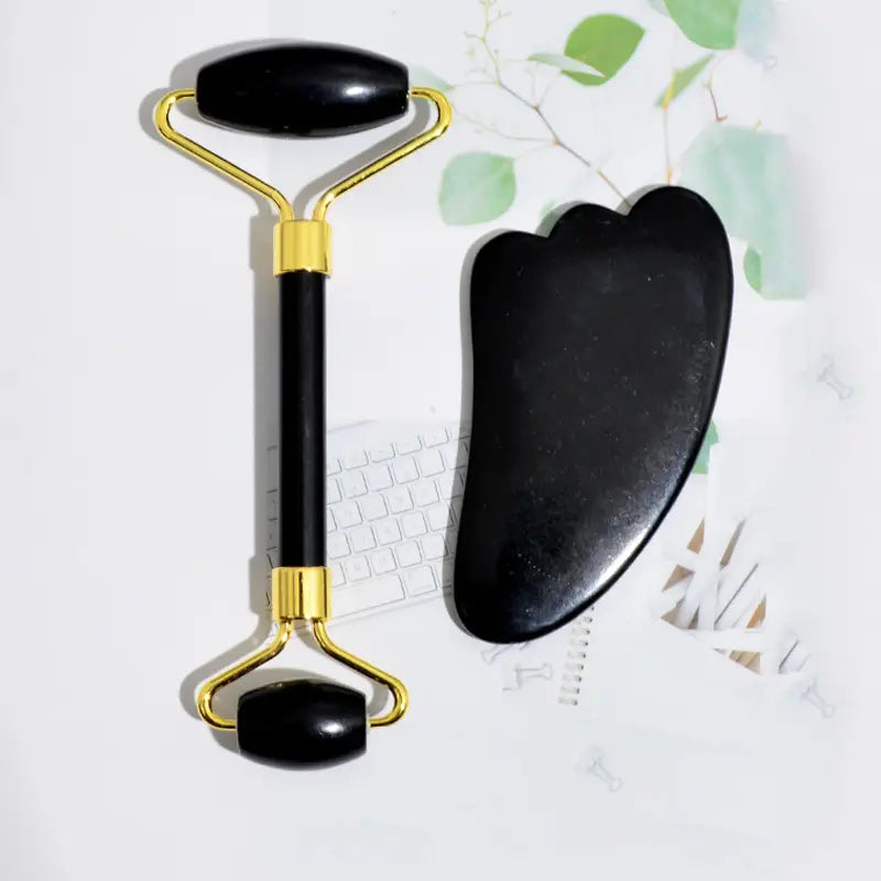 black obsidian beauty face care massage jade roller with a gold-tone metal frame and matching black stone foot massage tool for face care massage and relaxation.