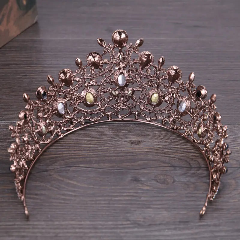 A rose gold vintage elegant sapphire diamond bridal crown tiara adorned with intricate filigree and sparkling clear and amber-colored crystals.