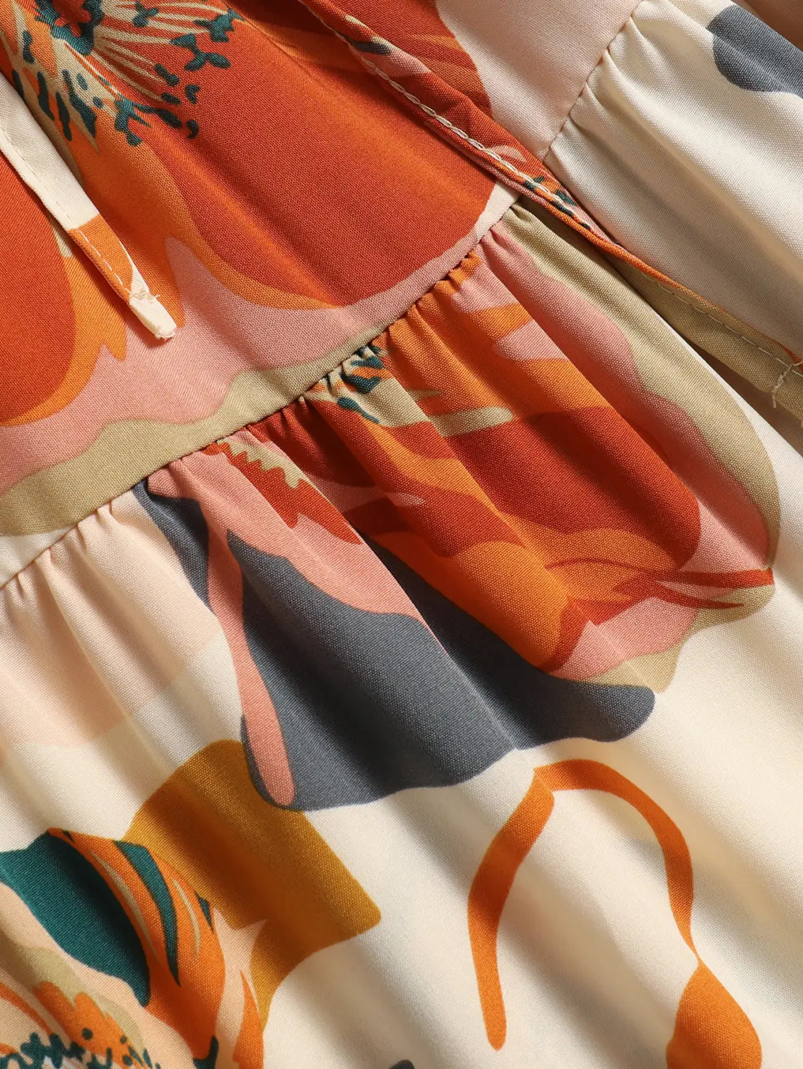 a cream tiered pleated floral print skirt featuring vibrant orange and cream abstract botanical motifs with a floral print elastic waist