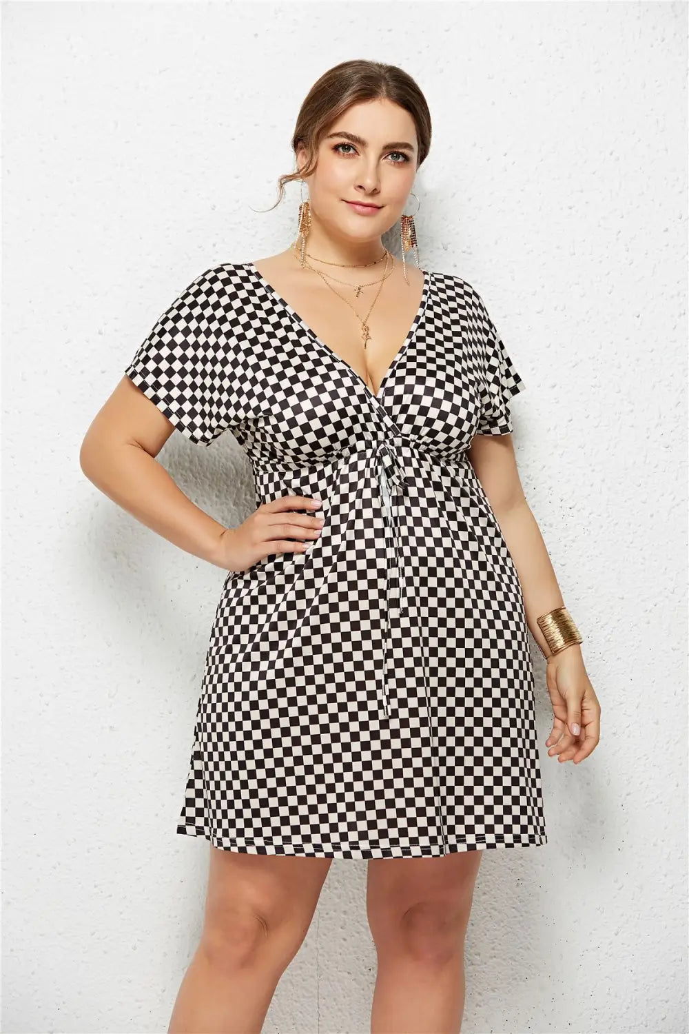 black and white checkered short-sleeved dress with a deep v-neck and elastic waist tie featuring a printed deep geometric design