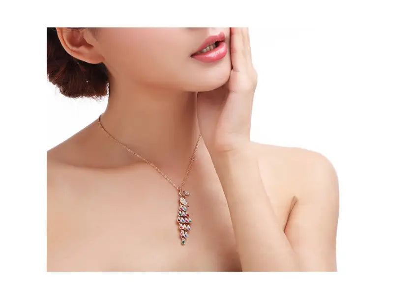 A delicate rose gold necklace from the creative crystal peacock bridal jewelry set features a cascading pendant adorned with multicolored gemstones.