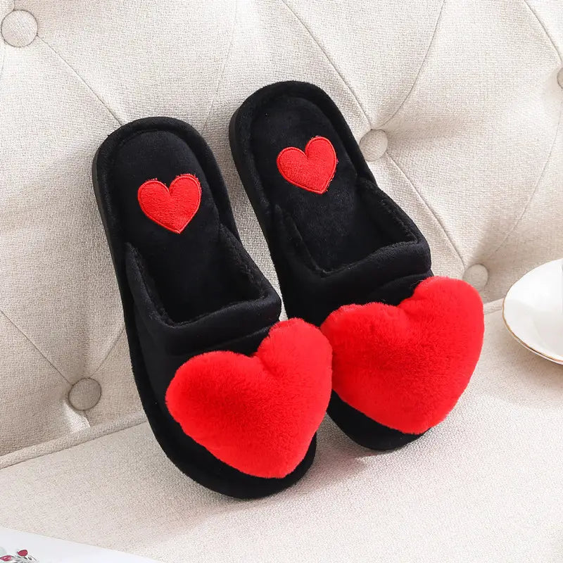 black plush home slippers with bright red fluffy heart decorations on the front and a matching embroidered heart on the insole designed as cute love slipper winter warm plush heart home slippers