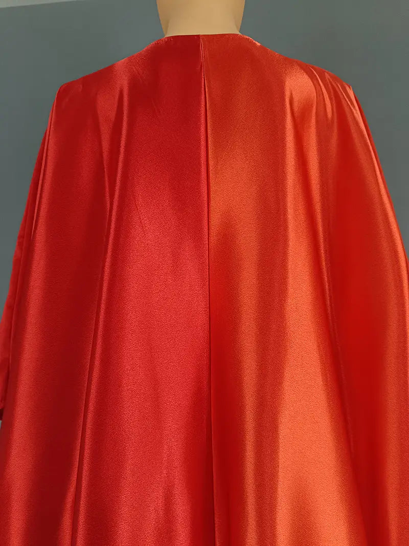 Back side of a vibrant red satin cape with a smooth glossy finish and a central seam.