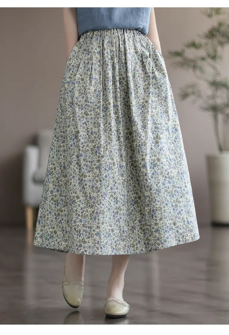 A flowing high-waisted midi skirt in soft gray artistic floral washed cotton fabric with delicate blue and white floral patterns.