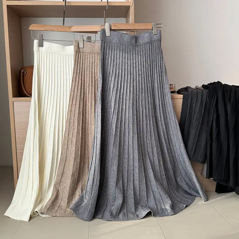 three pleated midi skirts in cream beige and metallic gray with korean elastic waist knitted design hang on wooden hangers