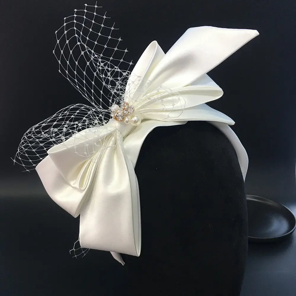 Elegant ivory satin wedding satin headband featuring a large bow, delicate lace veil, and sparkling crystal embellishment for fashion bridal wedding use
