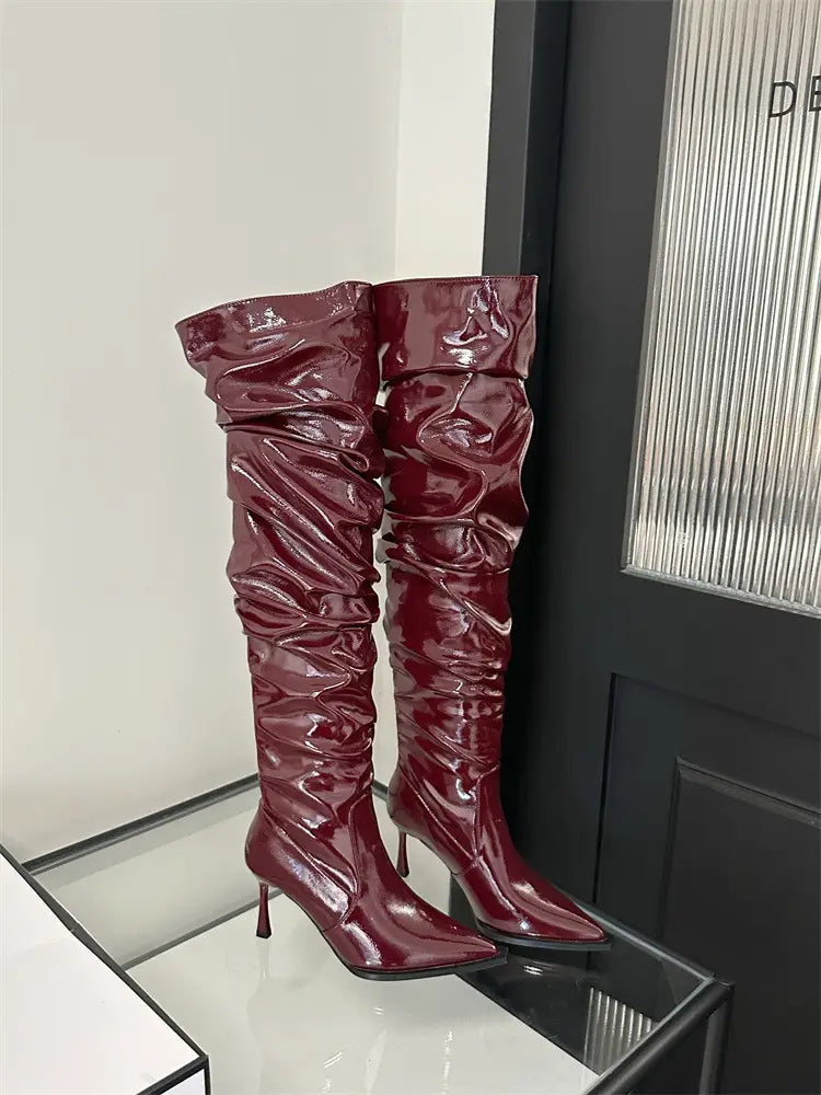 burgundy patent leather thigh high boots with a ruched glossy texture and pointed toe design featuring a stiletto heel pile style ideal for autumn stiletto heel fashion.