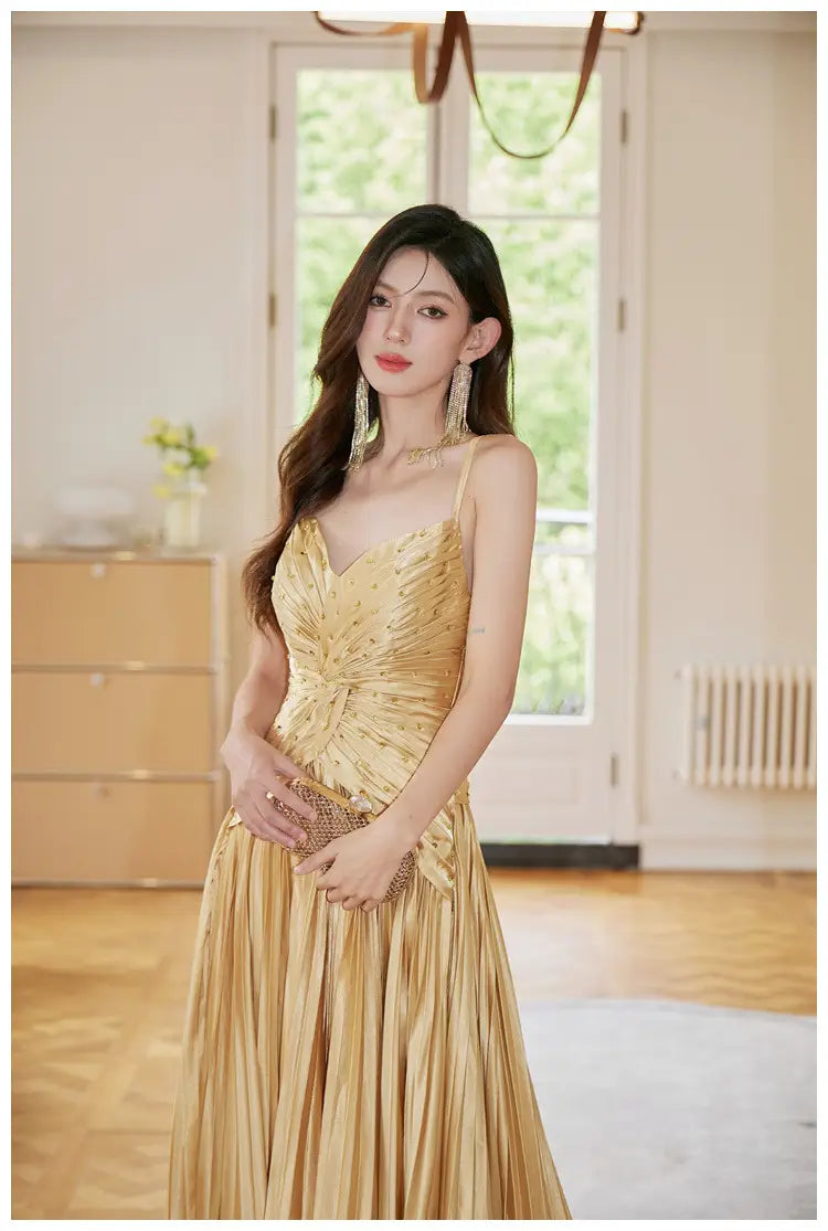 A shimmering gold satin heavy industry birthday dress featuring a fitted bodice and a flowing pleated skirt.