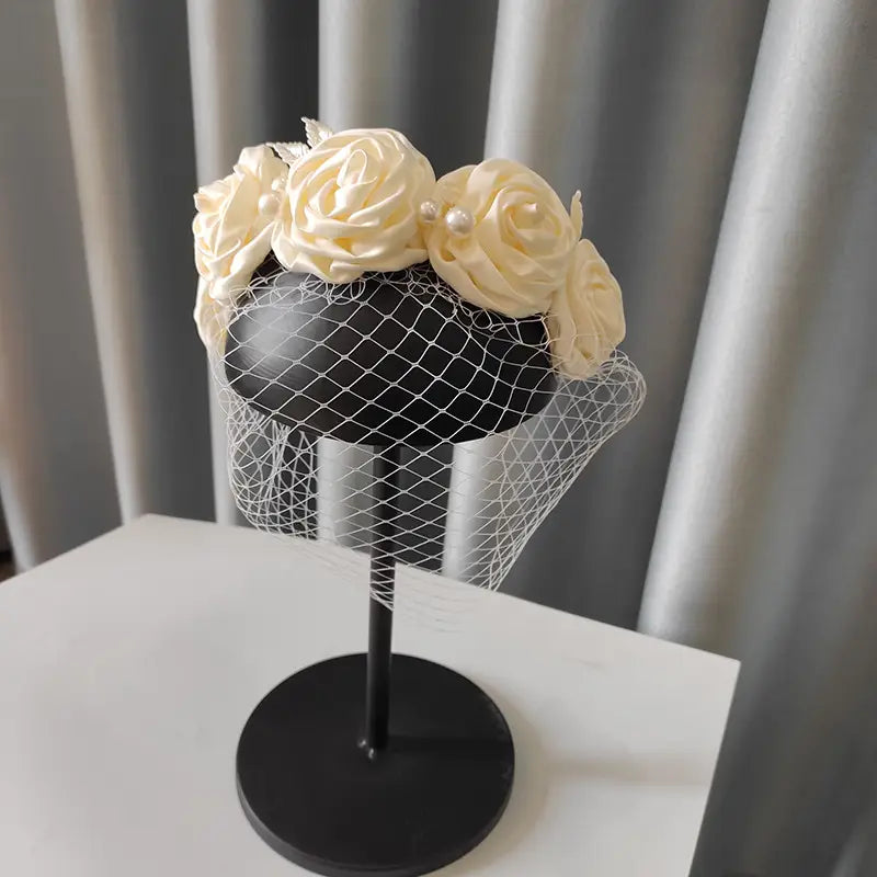 Elegant ivory satin rose hair hoop headdress adorned with delicate pearl accents and a fine black mesh veil for wedding dress accessories.