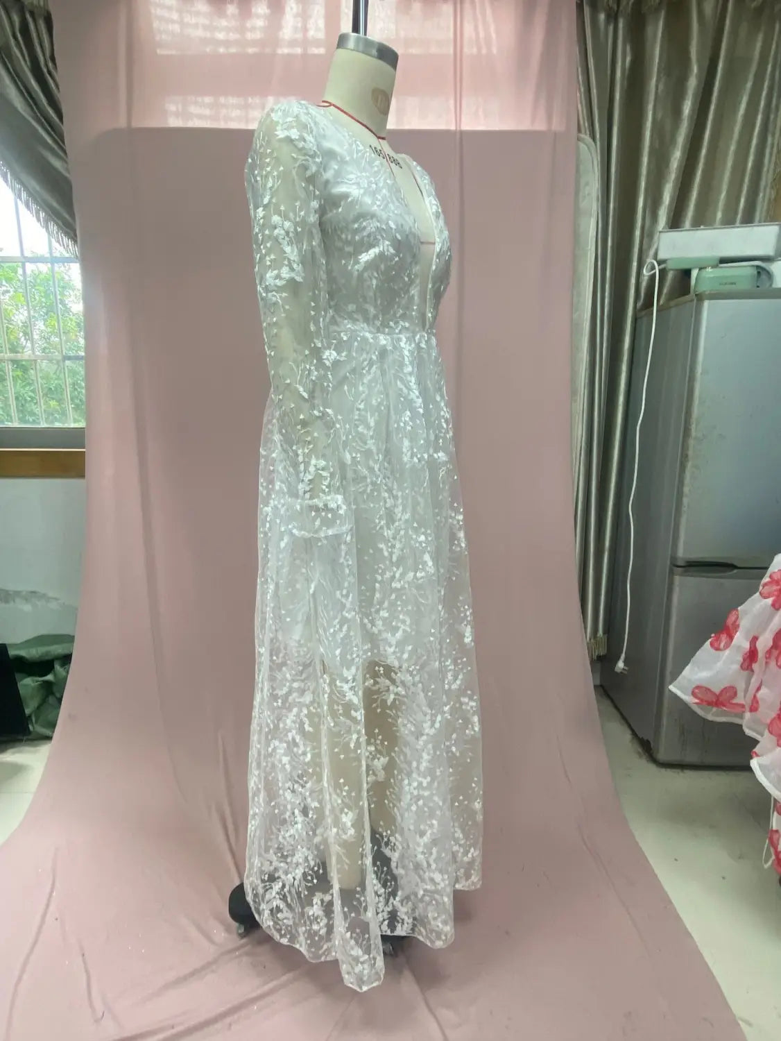 A delicate white long sleeve wedding dress lace gown with a fitted bodice and v neck displayed on a mannequin.