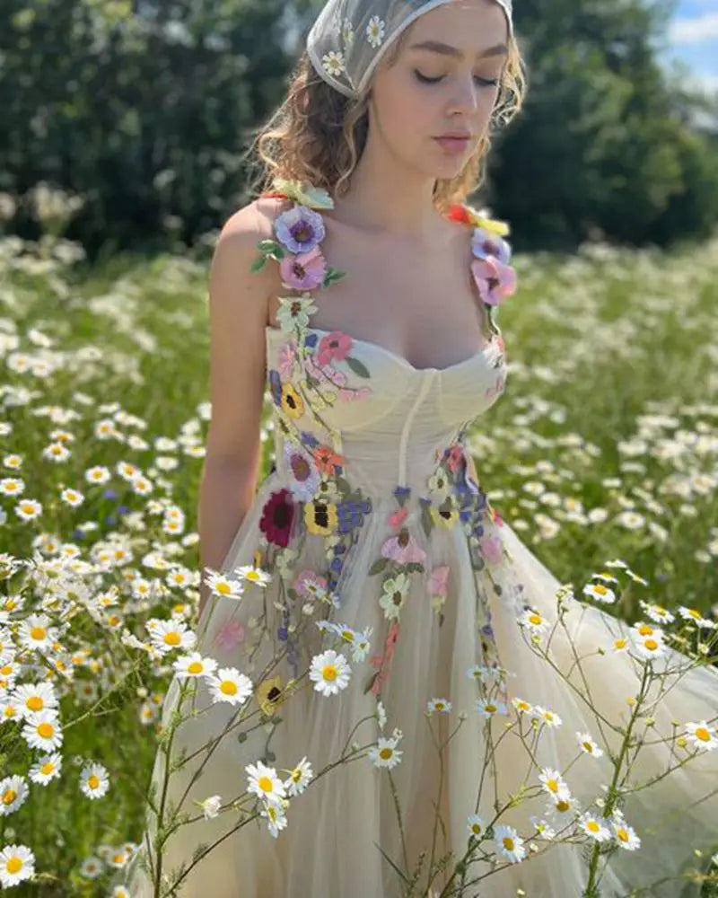 A delicate off-white floral gown featuring vibrant embroidered blossoms and a matching lace headpiece made of light champagne tulle for an elegant champagne tulle prom dress.