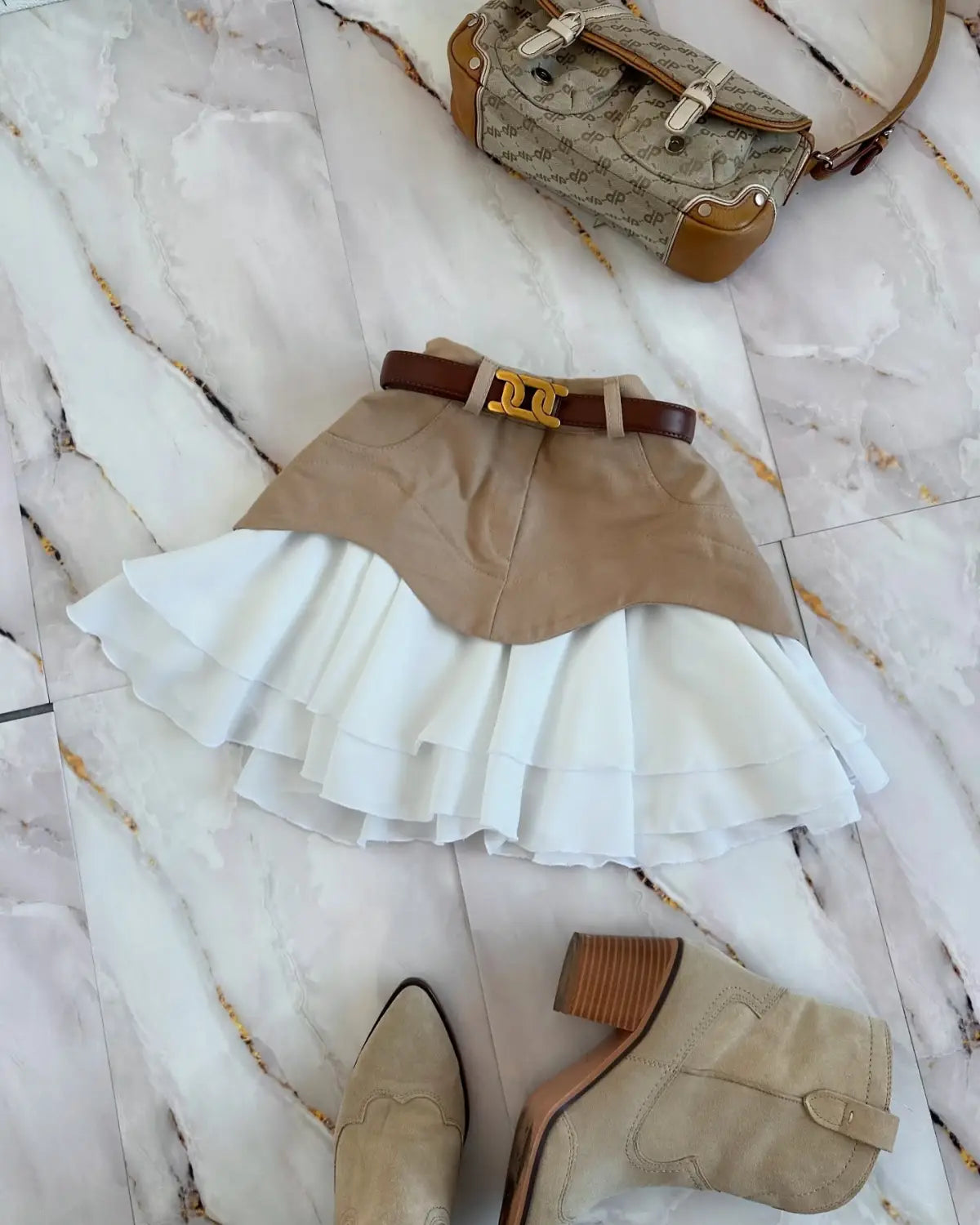 a beige and white two toned pleated mini skirt with a brown belt and gold tone buckle featuring a ruffled high waist and high waist tiered design