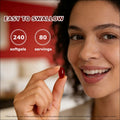 A glossy red cayenne pepper hawthorn berry softgel capsule held between fingers designed for easy swallowing