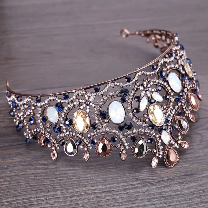An ornate vintage elegant sapphire and diamond bridal crown tiara in rose gold tone featuring deep blue amber and white opal-like stones set in intricate filigree.