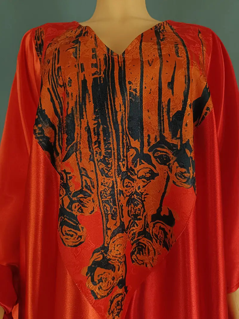 Vibrant orange satin kaftan featuring a bold black abstract face print in ethnic style loose plus size design.