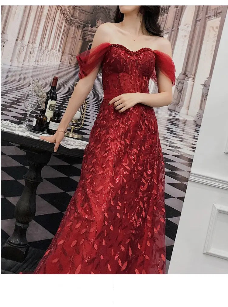 A shimmering red off-the-shoulder evening dress featuring intricate leaf-patterned lace and delicate sheer puff sleeves in a lace slim slimming bridal design.