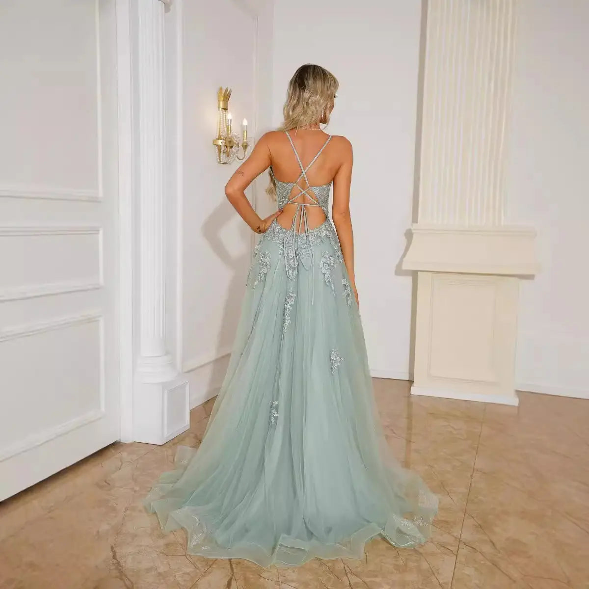 A delicate mint green lace women evening dress featuring intricate silver beading, a backless crisscross design, and a slit made of tulle for elegant evening wear suspender style.