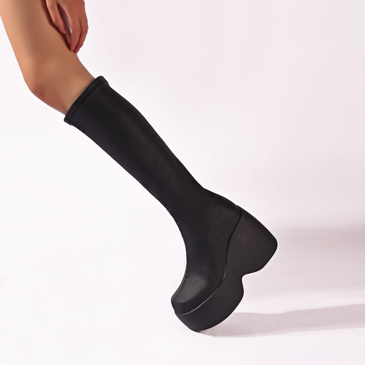 Black platform knee high elastic leather boots featuring a sleek stretchy upper and a thick block heel.
