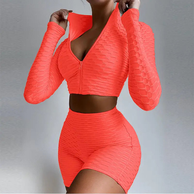 Vibrant coral-orange two-piece tummy control yoga activewear set with ribbed textured fabric and long sleeves designed for butt lift and support.