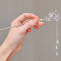 A delicate silver celestial moonstone xingx hairpin with intricate floral designs and dangling white teardrop beads
