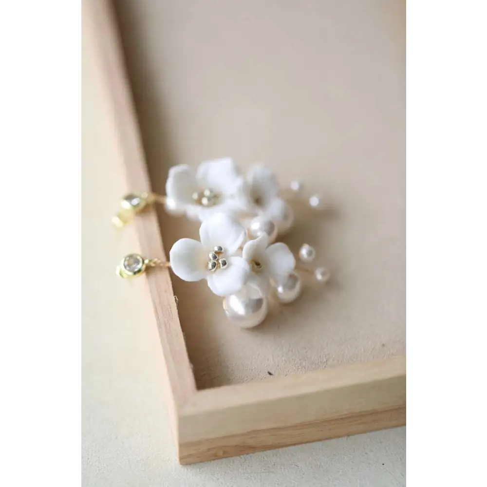 Delicate white ceramic flower pearl embellished bridal hairpin with gold-tone hardware and pearl accents