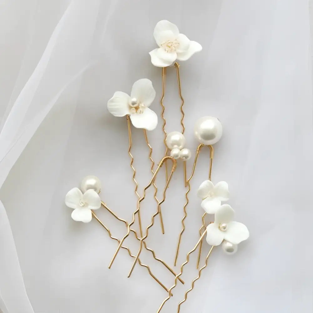 Elegant white ceramic flower pearl embellished bridal hairpin with gold-toned wire and delicate pearl accents