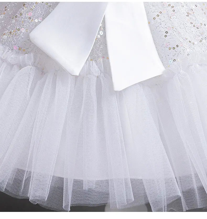 white wedding dress tulle featuring a silver sequined bodice, a white tulle skirt summer design, and a large satin bow.