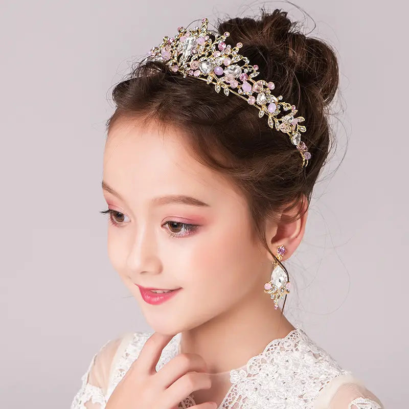 A delicate gold princess crown tiara featuring an intricate floral design adorned with sparkling pink and clear crystals for a catwalk cute princess look.