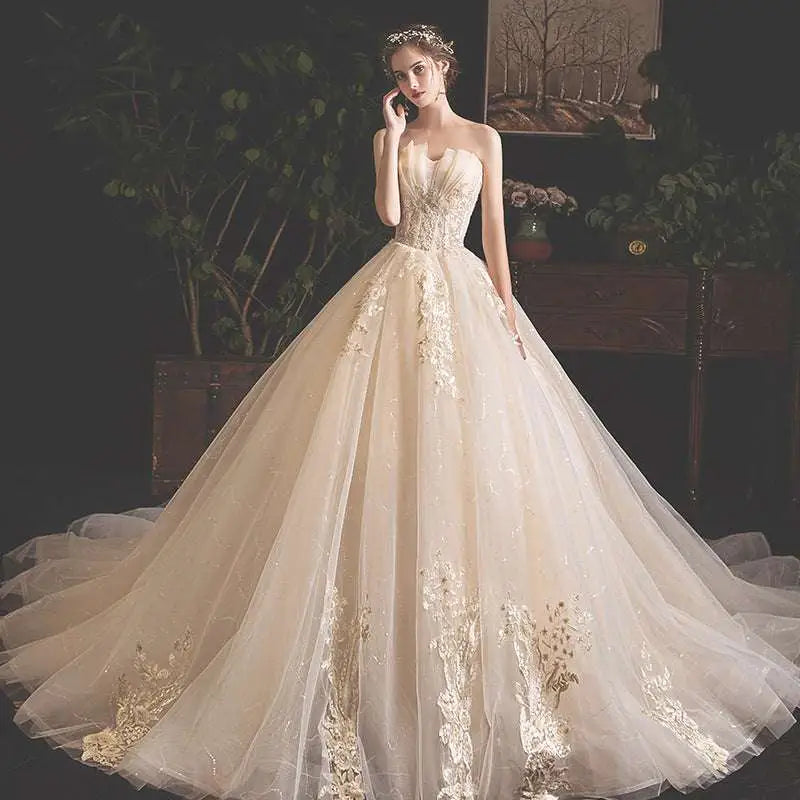 Strapless ivory champagne lace wedding gown with gold lace appliqués and voluminous tulle skirt for pregnant woman