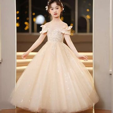 A young girl wearing a champagne sequined spandex princess dress with tulle tutu and ruffled sleeves