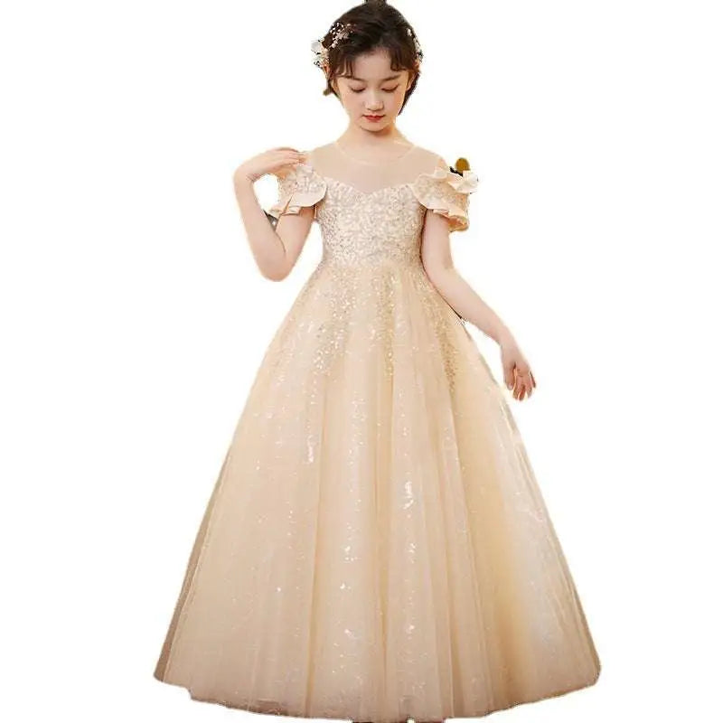 A young girl wearing a champagne sequined spandex princess dress with tulle tutu and ruffled sleeves
