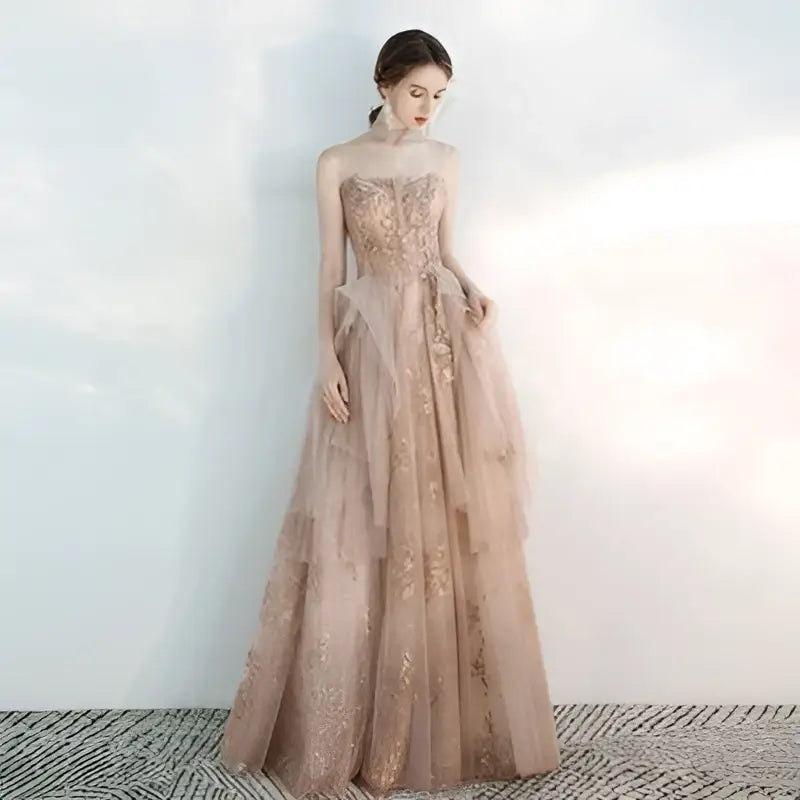 Strapless female wedding gown in champagne tulle toast with intricate gold embroidery and layered floor-length design