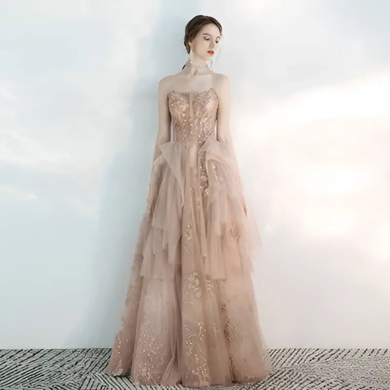 A strapless female wedding gown in champagne tulle toast with intricate gold embroidery and layered tulle fabric