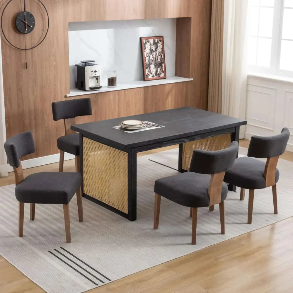 Black rectangular dining table with woven cane side panels and wooden legs paired with rivova linen dining chairs set of 4