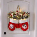 Red christmas mittens glove shaped wreath filled with festive greenery, red berries, pinecones, and twinkling lights for christmas garland creative decor